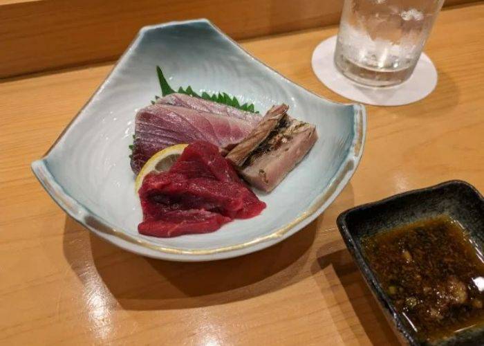 Fresh sashimi at Sushi Kourin, served alongside a dipping sauce and ice-cold water.